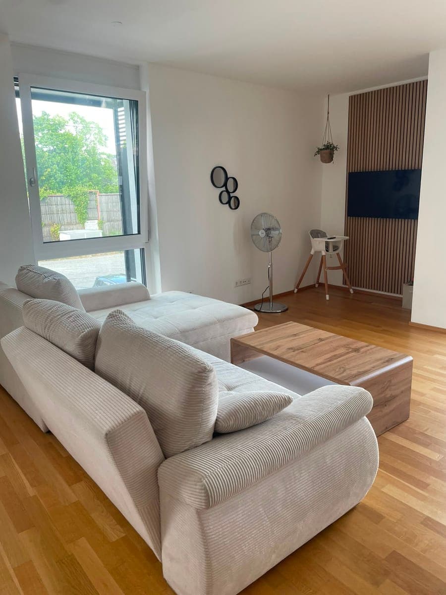 Phone shot of a living room with a corduroy sofa: the window is blown out and the room looks yellowish