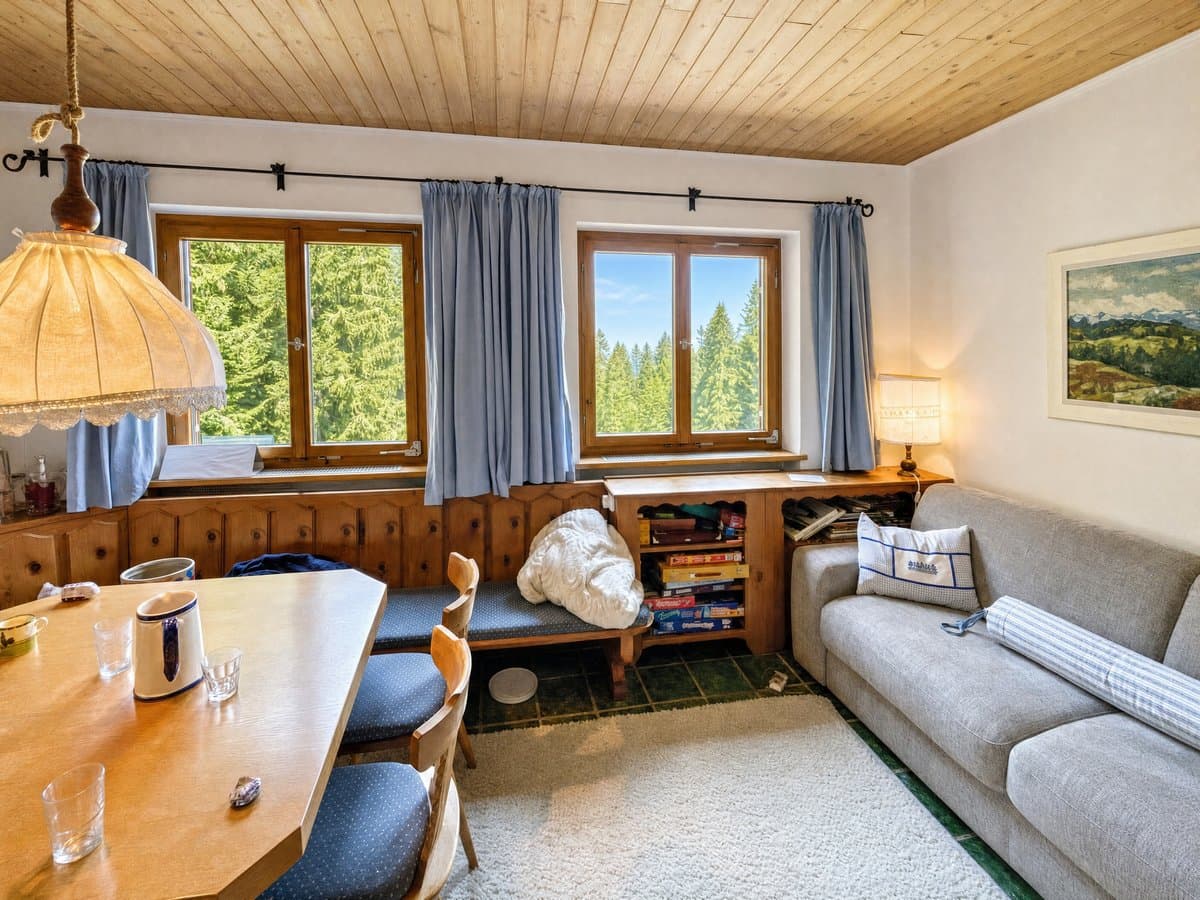 Wohnzimmer einer Berghütte mit Decke, Kleidung und Gläsern auf Bank und Tisch