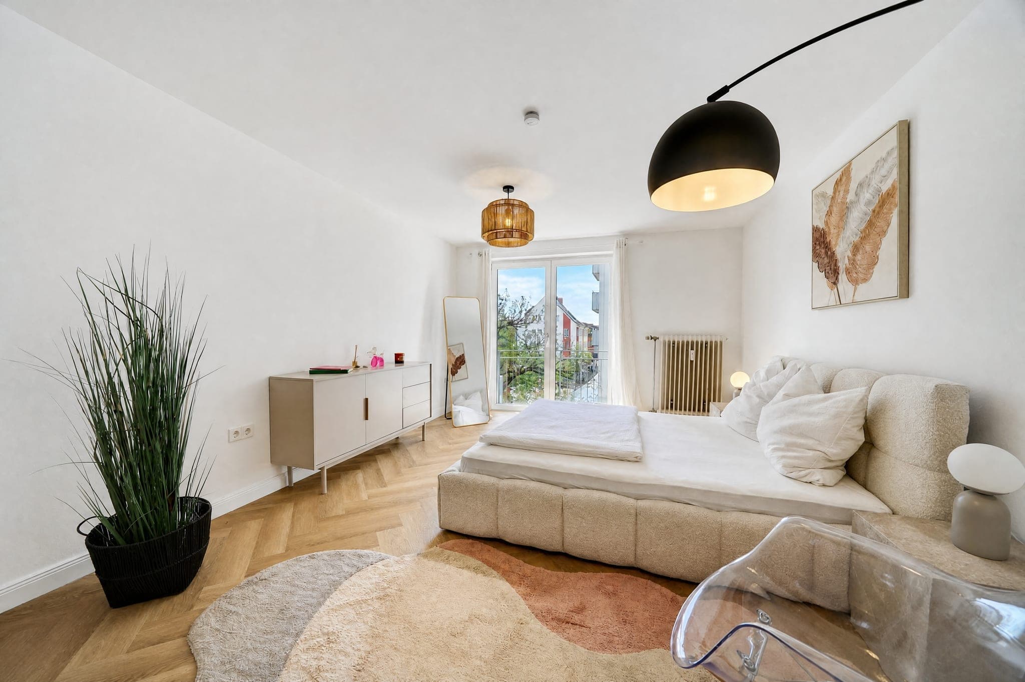 Bedroom with an upholstered bed, sideboard and floor mirror on herringbone parquet