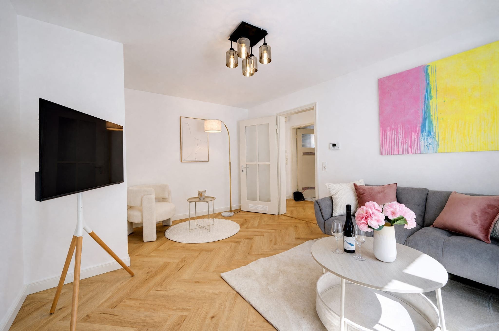 Living area with a wall-mounted TV, grey sofa and round side tables