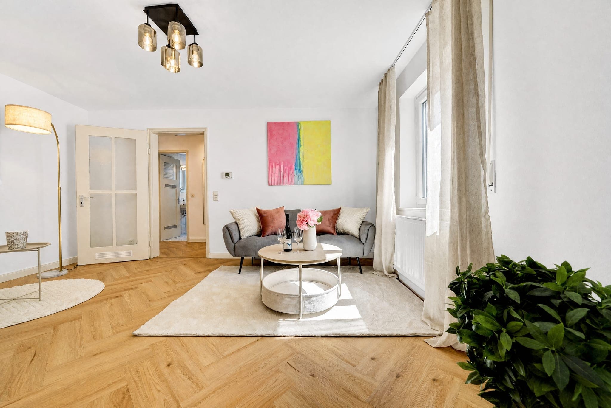 Living room with a sofa, floor-length curtains and a colourful canvas