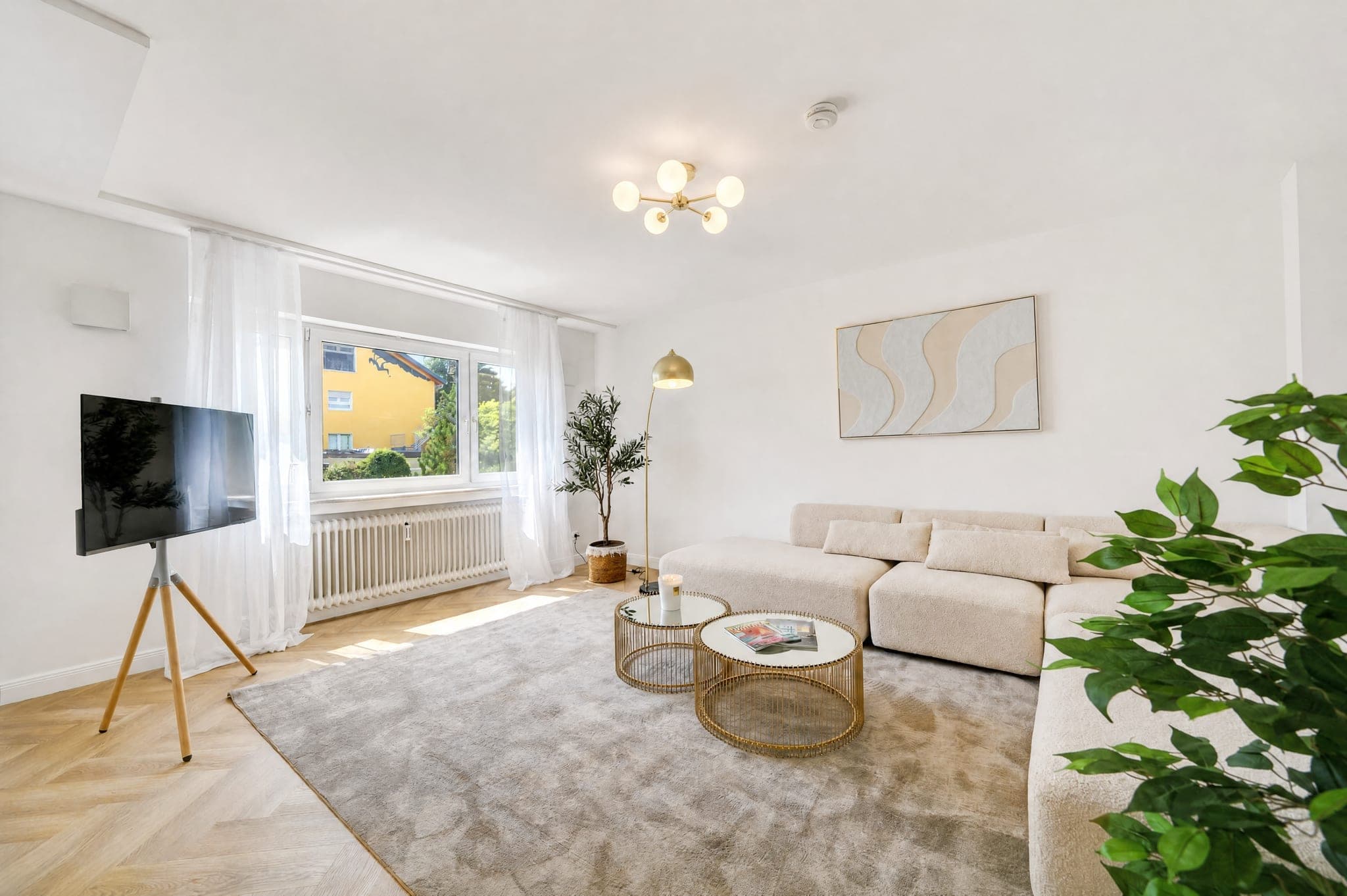 Living room with a modular sofa, TV and a window front onto greenery