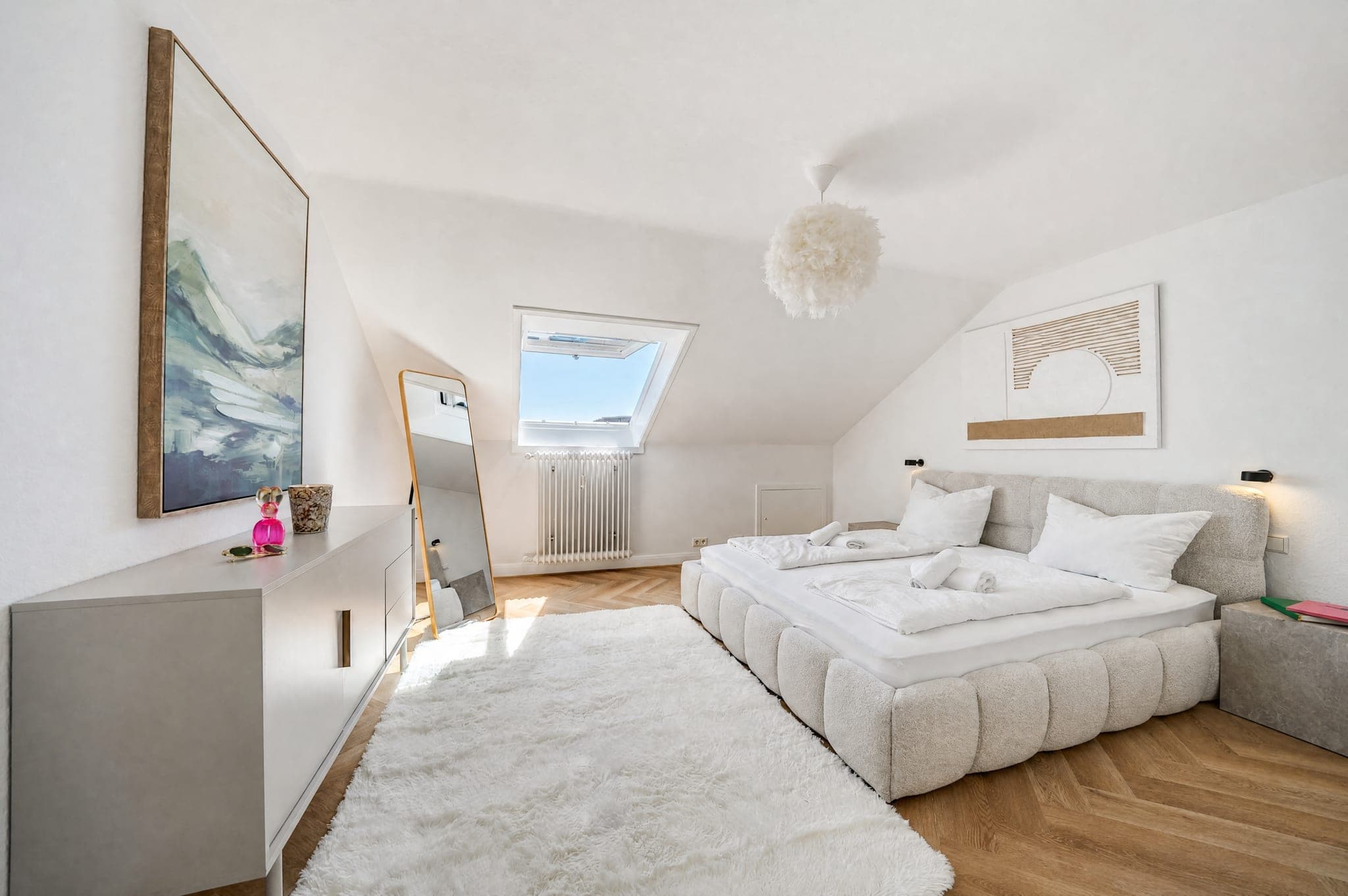 Attic bedroom with an upholstered bed under the slope and a roof window