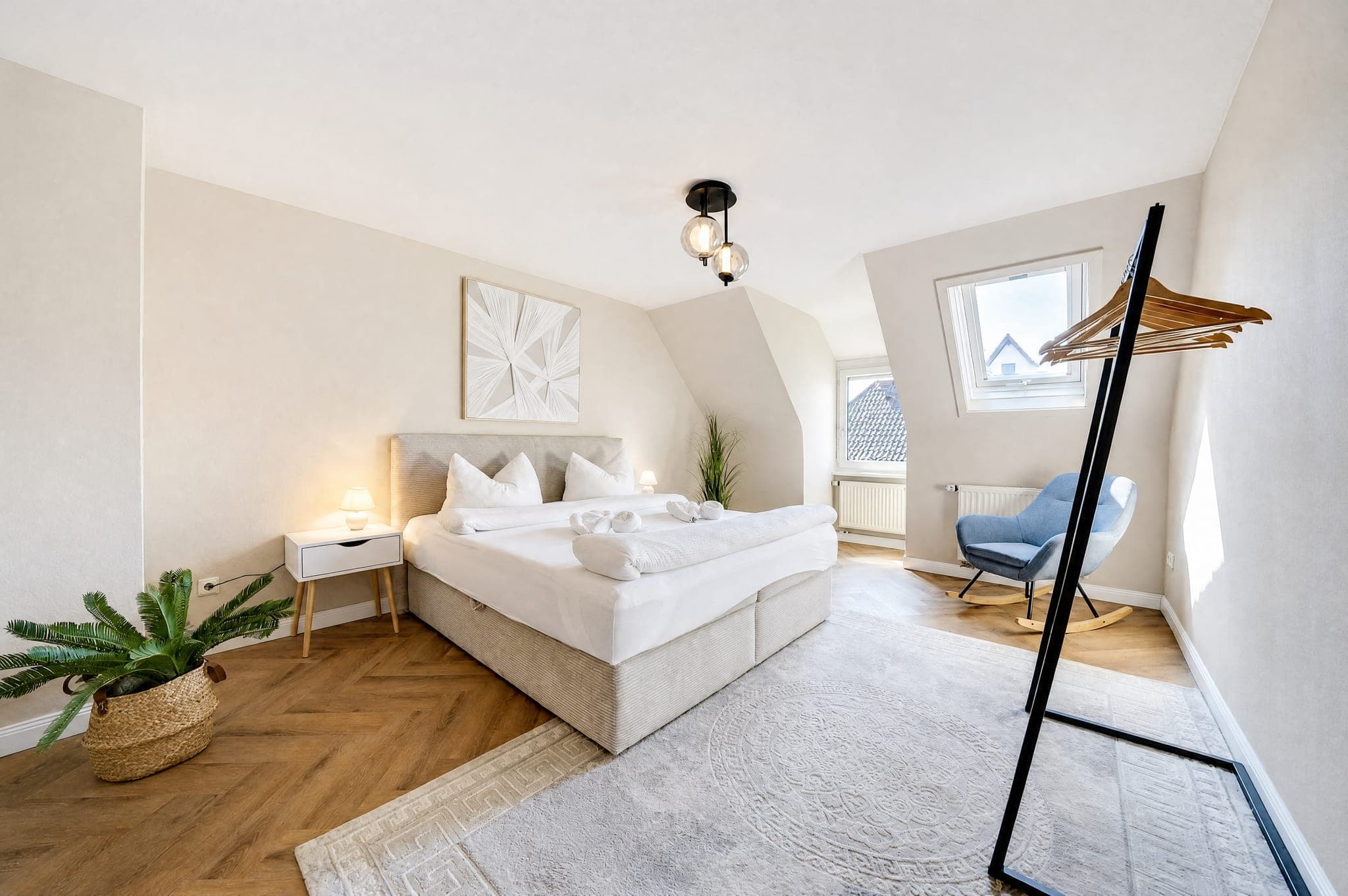 Bedroom with a box-spring bed and an armchair at the roof window on herringbone parquet
