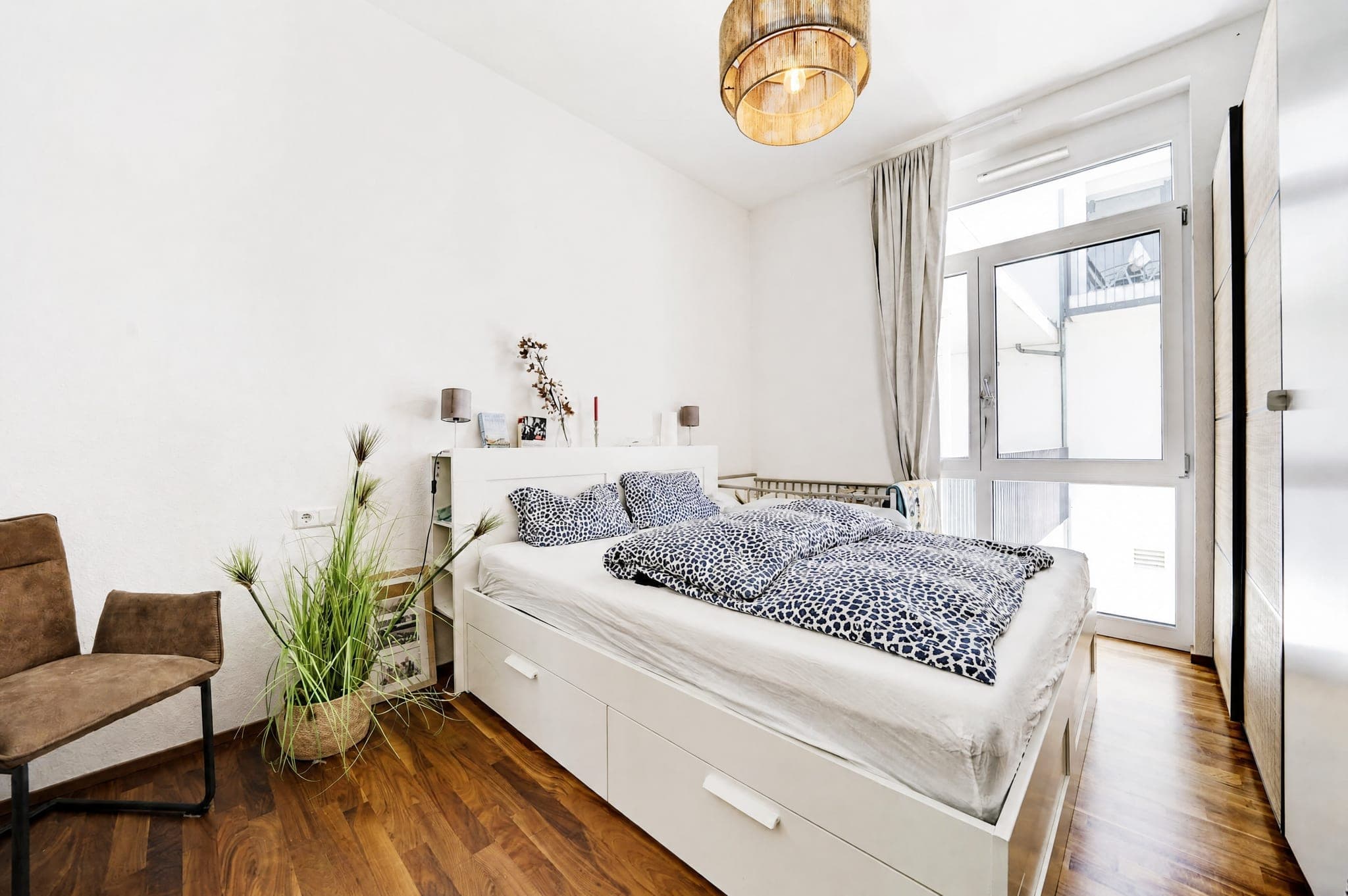 Bedroom with a storage bed, patterned bedding and a balcony door