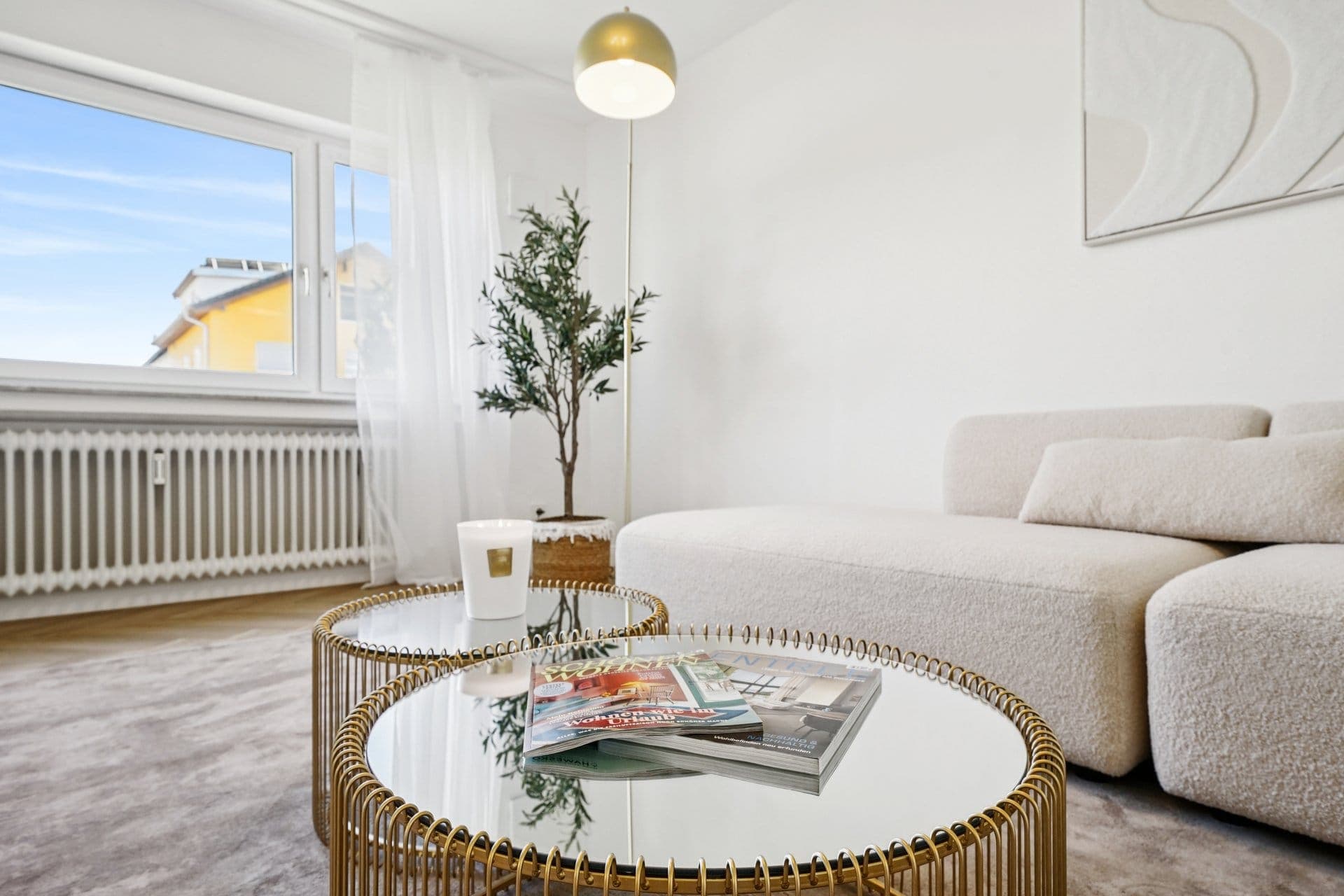 Living area with a bouclé sofa and a round coffee table in front of the window