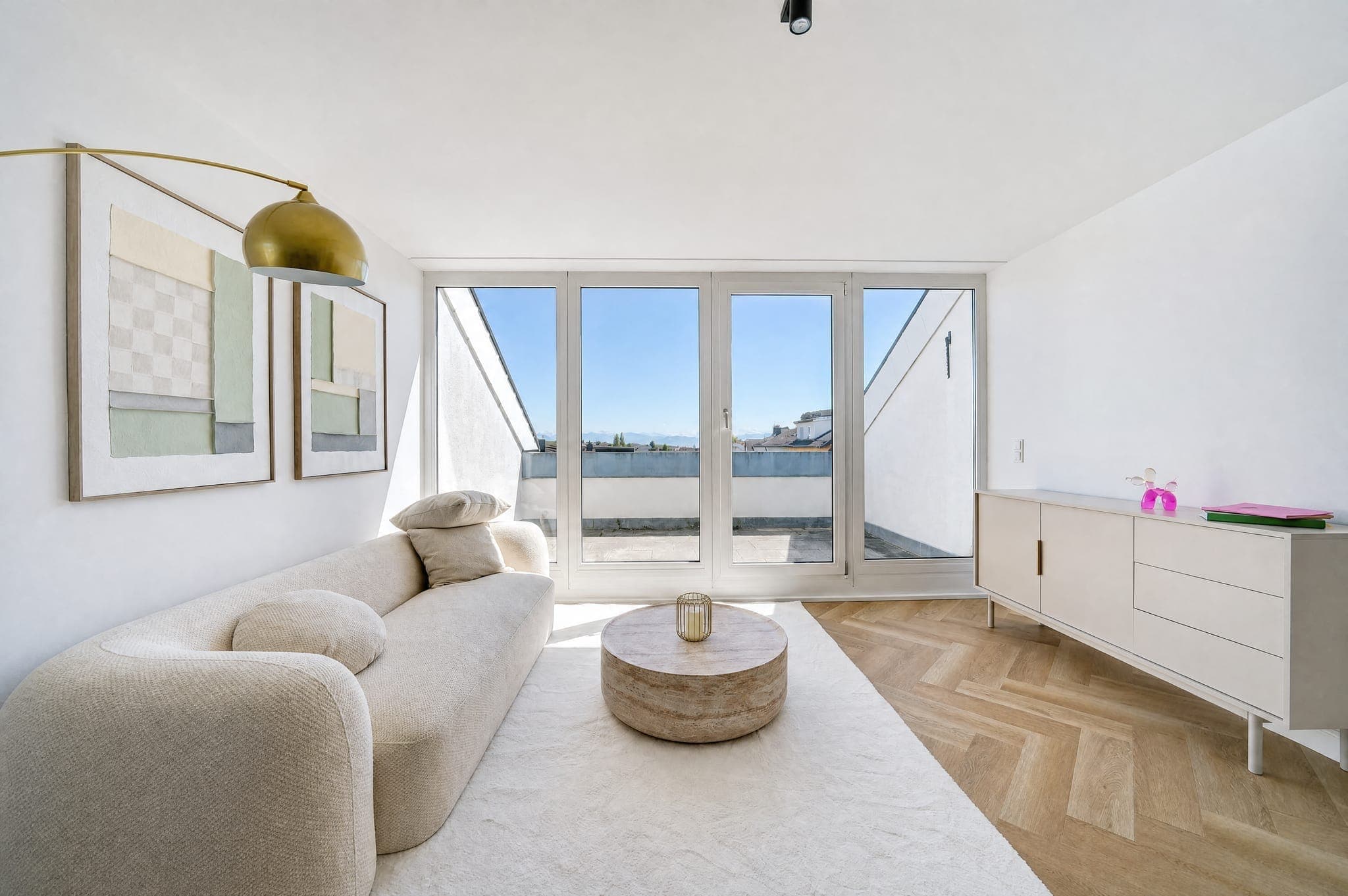 Living room with a rounded sofa in front of the window onto the roof terrace, blue sky held