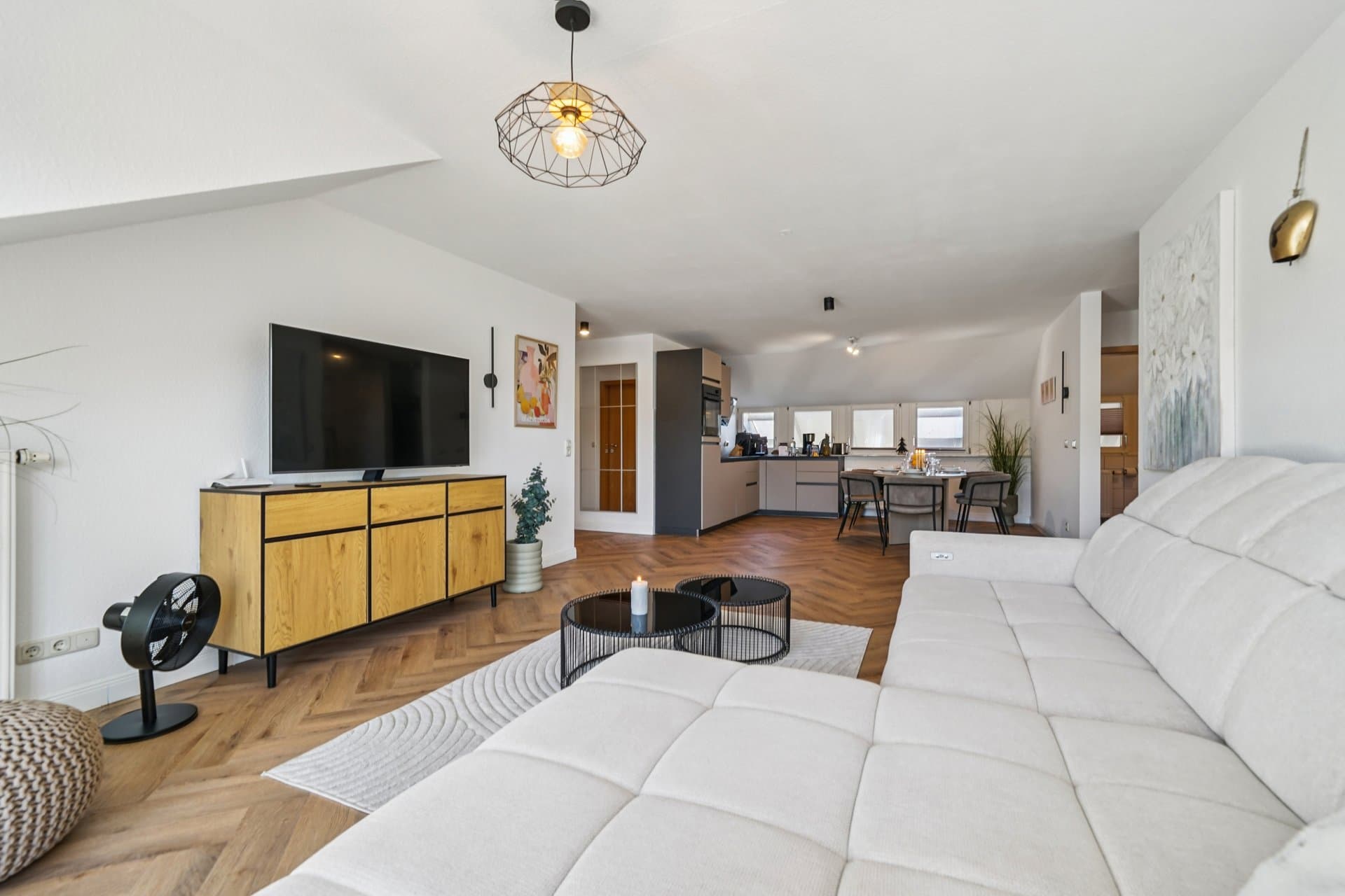 Open living area with a large white upholstered sofa and a clear view through to the kitchen