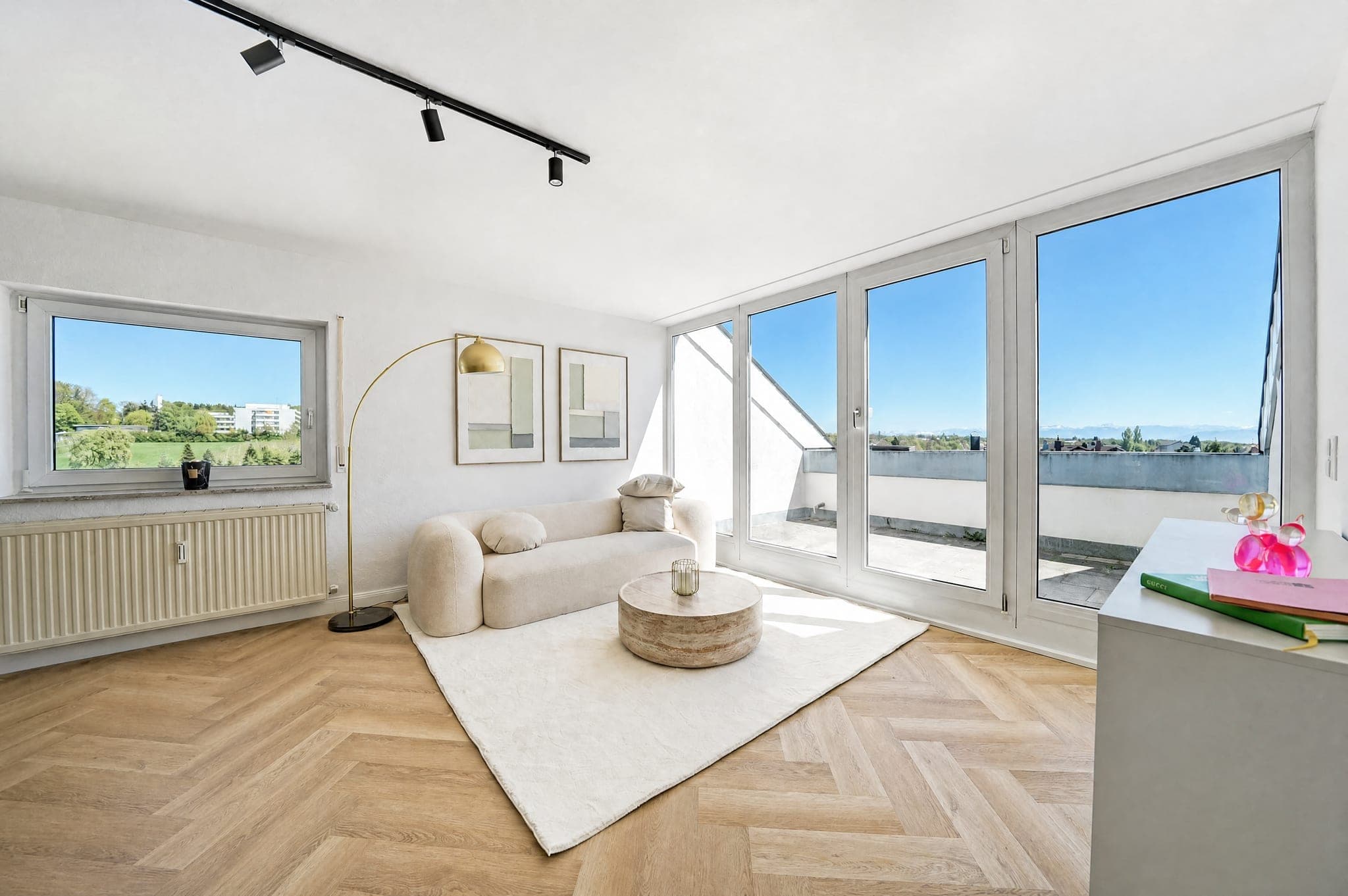 Living room with a floor-to-ceiling window front onto the roof terrace — interior and blue sky correctly exposed at once