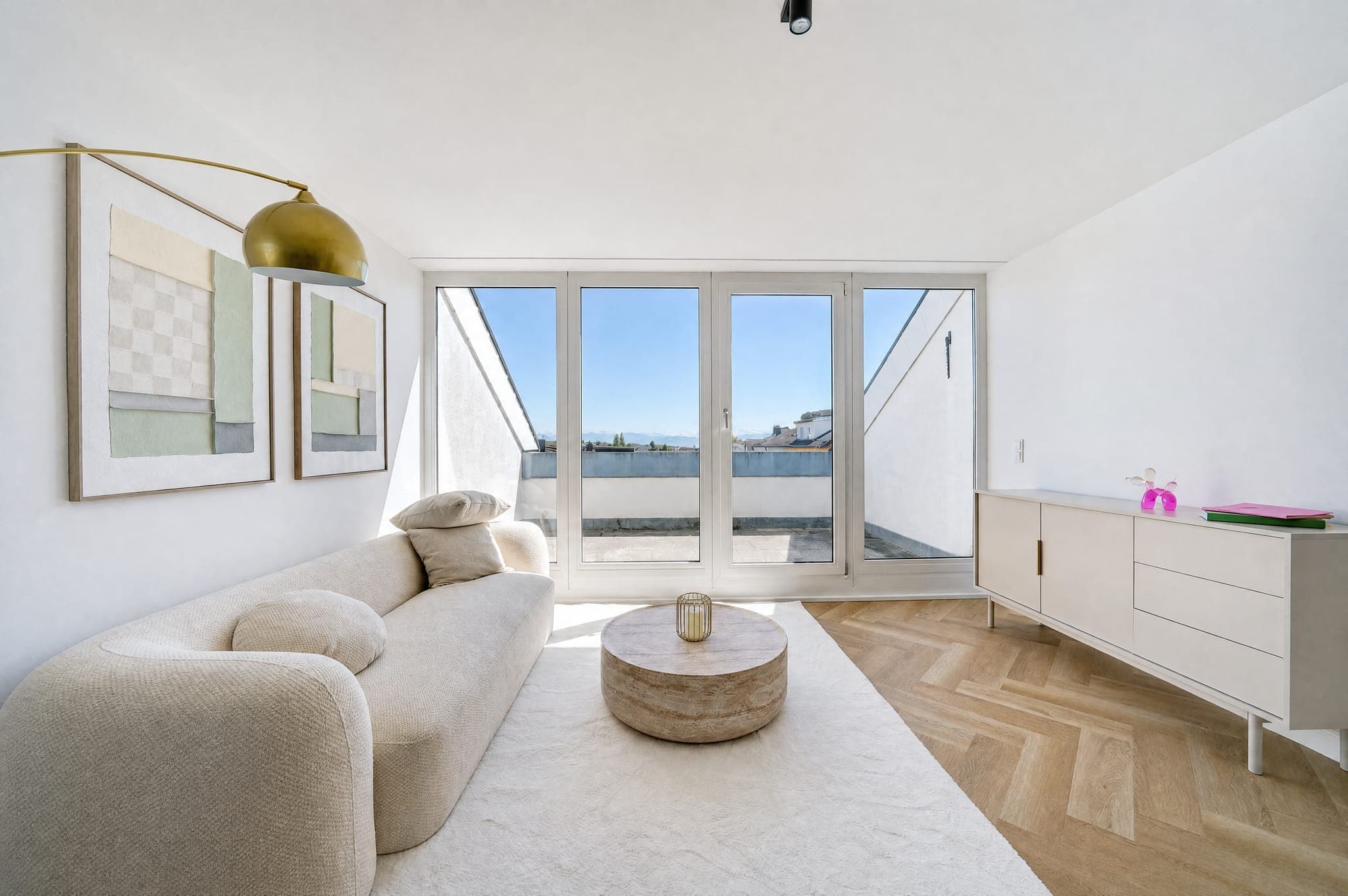 Living area with a rounded sofa and sideboard in front of the window onto the roof terrace