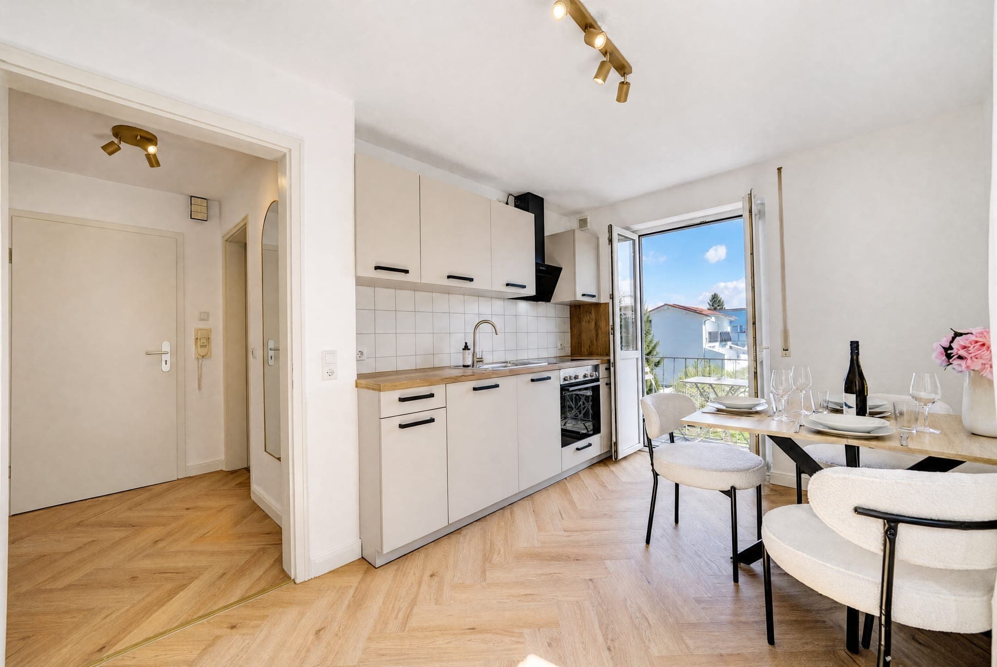 Run of kitchen units with a dining spot at the balcony window on herringbone parquet